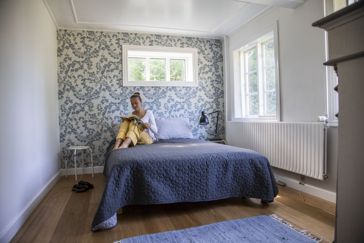 Smilla sidder og læser på seng i et af værelserne på Styrmandsgården