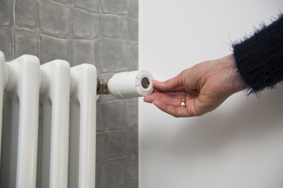 Kvinde indstiller intelligent termostat på radiator